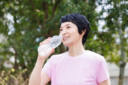Téléchargez les photos : Asiatique femme potable eau après jogging - en image libre de droit