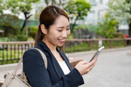 Portrait de belle femme d'affaires japonaise en costume utilisant un téléphone portable dans la rue