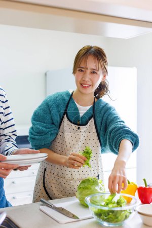 Téléchargez les photos : Couple préparant une salade de légumes frais dans la cuisine - en image libre de droit