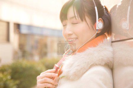 Téléchargez les photos : Femme écoutant la musique avec des écouteurs à l'extérieur - en image libre de droit