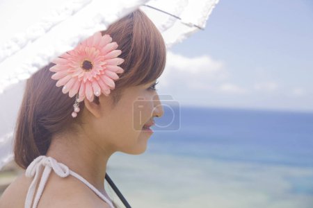 Foto de Retrato de hermosa joven japonesa con paraguas en la orilla del mar durante las vacaciones de verano - Imagen libre de derechos