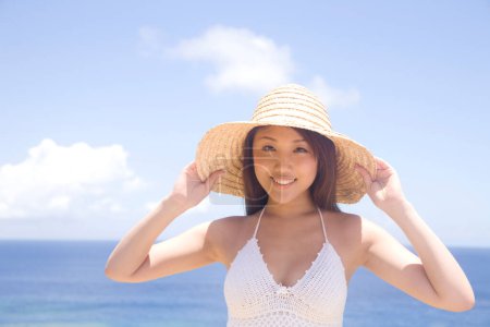 Téléchargez les photos : Belle asiatique femme portant paille chapeau posant sur plage - en image libre de droit