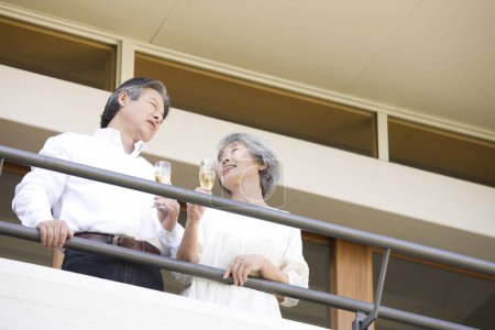 Téléchargez les photos : Senior asiatique couple en amour sur balcon boire champagne - en image libre de droit