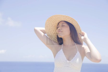 Téléchargez les photos : Belle asiatique femme portant paille chapeau posant sur plage - en image libre de droit