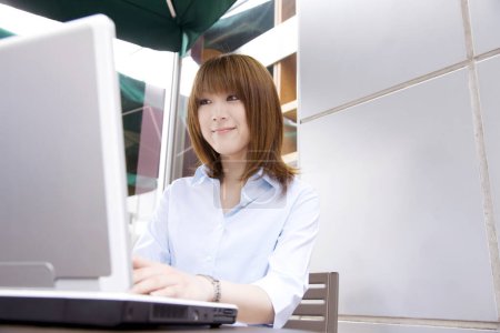 Téléchargez les photos : Femme utilisant un ordinateur portable dans un café - en image libre de droit