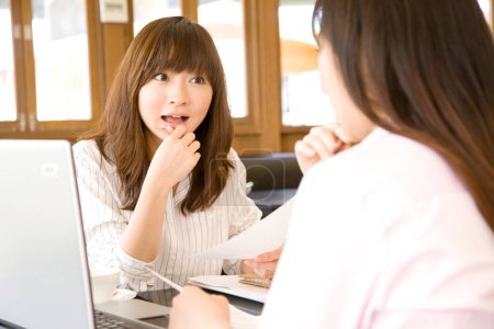 Téléchargez les photos : Deux femmes d'affaires japonaises travaillant avec un ordinateur portable dans un café - en image libre de droit