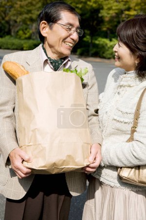 Téléchargez les photos : Asiatique senior couple dans l'amour avec shopping sac plein de épicerie - en image libre de droit