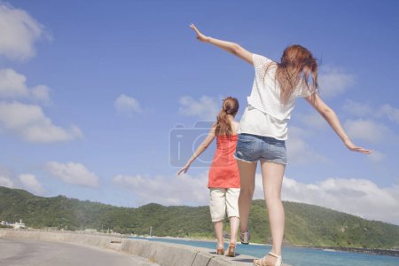 Foto de Dos mujeres asiáticas caminando por la playa con los brazos extendidos - Imagen libre de derechos