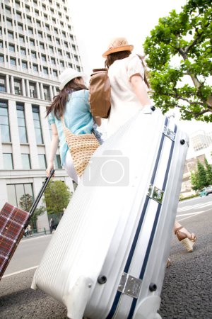 Foto de Mujeres con maletas caminando por la calle de la ciudad - Imagen libre de derechos