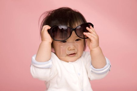 Photo for Asian little girl with sunglasses on pink background - Royalty Free Image