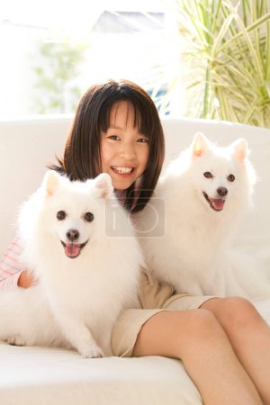 Foto de Feliz asiático chica con dos japonesa spitz en casa - Imagen libre de derechos