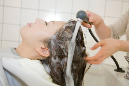Téléchargez les photos : Jeune femme japonaise faisant coiffure dans le salon. Beauté dame japonaise faisant coiffure élégante - en image libre de droit