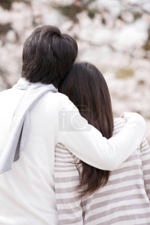 Foto de Retrato de feliz joven pareja japonesa pasar tiempo juntos en el parque durante la flor de sakura - Imagen libre de derechos