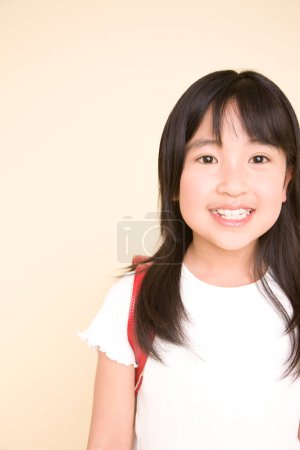 Photo for Asian schoolgirl smiling and looking at camera isolated on white background - Royalty Free Image