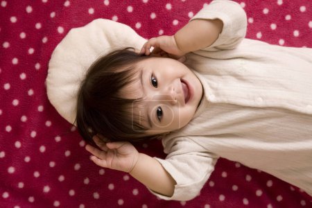 Foto de Lindo poco asiático bebé acostado en cama en casa - Imagen libre de derechos