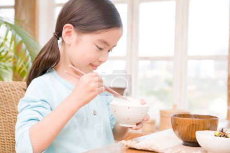 Foto de Poco asiático chica comer arroz - Imagen libre de derechos