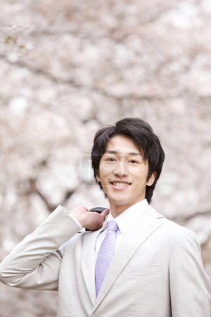 Foto de Retrato de un joven empresario japonés en el parque durante la flor de sakura en primavera - Imagen libre de derechos