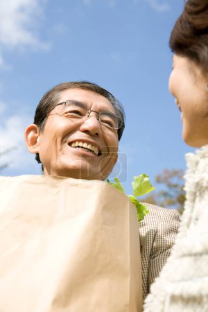 Photo for Asian senior couple in love with shopping bag full of groceries - Royalty Free Image