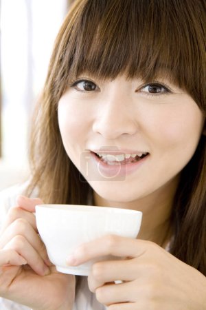 Photo for Close up view of young Japanese woman with cup of tea in cafe - Royalty Free Image