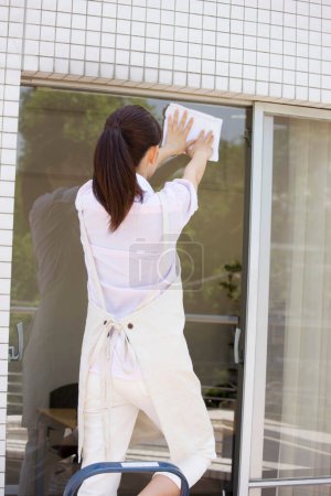 Foto de Joven japonesa mujer limpiando ventana - Imagen libre de derechos
