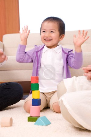asian family grandfather and granmother playing with their grandson on the floor with wooden cubes
