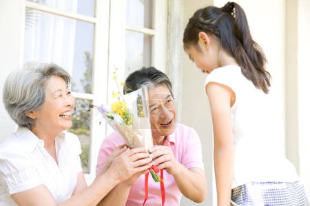 Téléchargez les photos : Petite-fille donnant des fleurs aux grands-parents - en image libre de droit