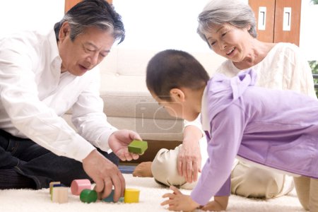 asiatische Familie Großvater und Großmutter spielen mit ihrem Enkel auf dem Boden mit Holzwürfeln