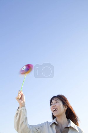 Photo for Young woman playing with a windmill toy - Royalty Free Image