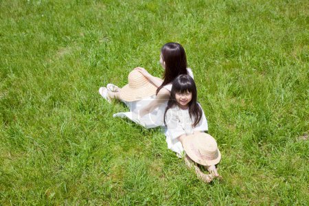 Téléchargez les photos : Jeune femme asiatique en robe blanche et fille posant dans le champ vert. - en image libre de droit