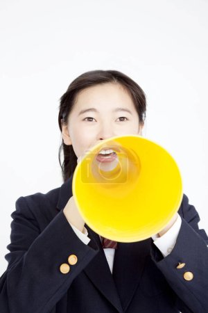 Foto de Portrait of Japanese school girl with loudspeaker on white studio background - Imagen libre de derechos