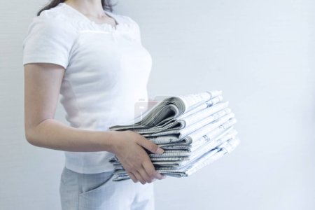 Foto de Joven mujer sosteniendo pila de periódicos en las manos - Imagen libre de derechos