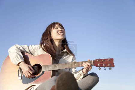 Foto de Mujer joven tocando la guitarra acústica - Imagen libre de derechos