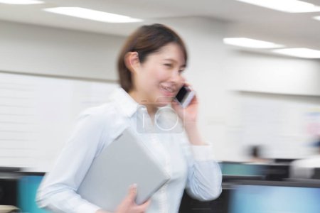 Téléchargez les photos : Jeune asiatique femme parler sur téléphone dans moderne bureau - en image libre de droit