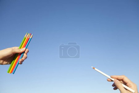 Photo for Two hands hold colorful colored pencils. - Royalty Free Image
