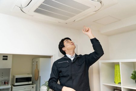 Photo for Asian man installing air conditioning on the ceiling - Royalty Free Image