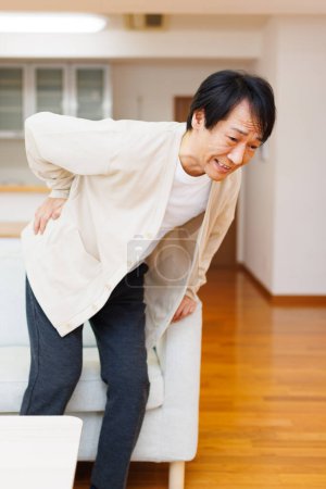 Foto de Mayor asiático hombre sufriendo de dolor de espalda en el hogar - Imagen libre de derechos