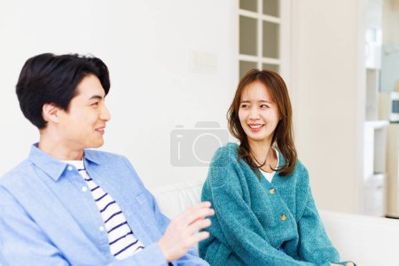 Foto de Joven pareja japonesa sentado en sofá en casa - Imagen libre de derechos