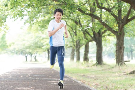 Foto de Deportivo japonés hombre corriendo en verano parque - Imagen libre de derechos