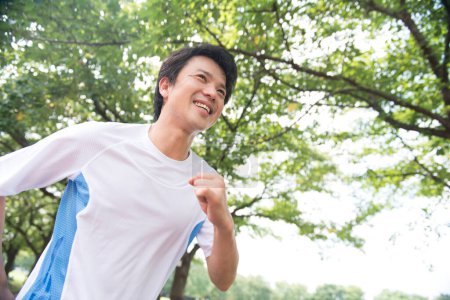 Téléchargez les photos : Homme japonais sportif jogging dans le parc d'été - en image libre de droit