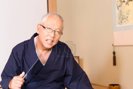 retrato de un anciano asiático hombre con abanico de madera