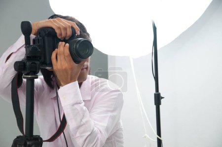 Foto de Asiático joven guapo macho fotógrafo hold DSLR cámara en manos - Imagen libre de derechos