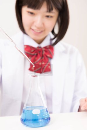 Téléchargez les photos : Asiatique femelle étudiant tenant pipette pendant chimie leçon - en image libre de droit