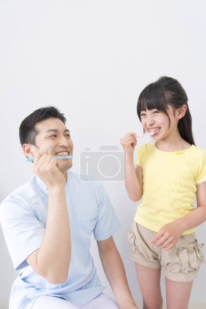 Téléchargez les photos : Portrait en studio d'un jeune médecin enseignant à un petit patient comment se brosser les dents - en image libre de droit