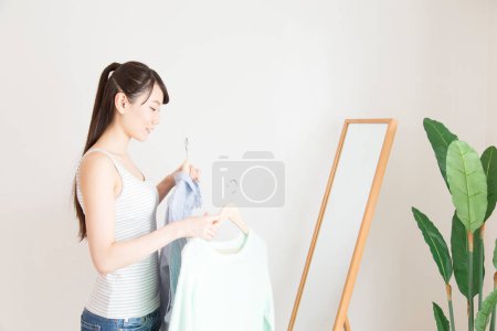 Téléchargez les photos : Femme choisissant les vêtements par miroir - en image libre de droit