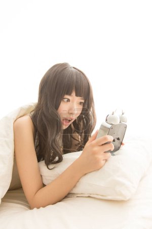 Téléchargez les photos : Jeune femme avec réveil dans le lit - en image libre de droit