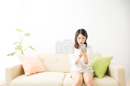 Téléchargez les photos : Portrait de belle jeune femme asiatique en utilisant smartphone isolé sur blanc - en image libre de droit