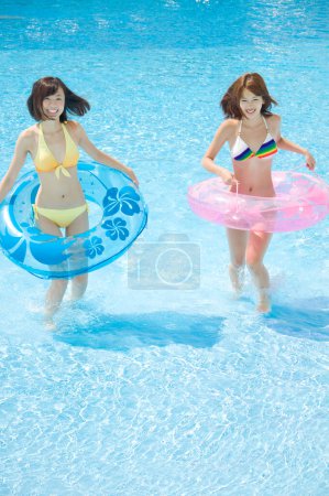 Photo for Beautiful Japanese women in colorful swimsuits having fun at pool, vacationing concept - Royalty Free Image