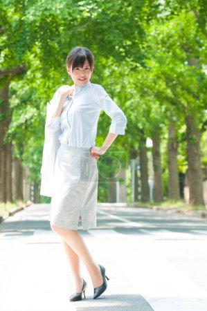 Téléchargez les photos : Portrait extérieur d'une femme japonaise joyeuse marchant dans un parc d'été verdoyant - en image libre de droit