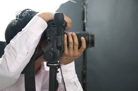 Photo for Asian young handsome male photographer hold DSLR camera in hands - Royalty Free Image