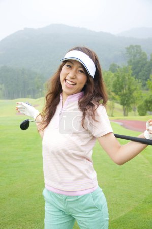 Photo for Asian woman playing golf on green field - Royalty Free Image